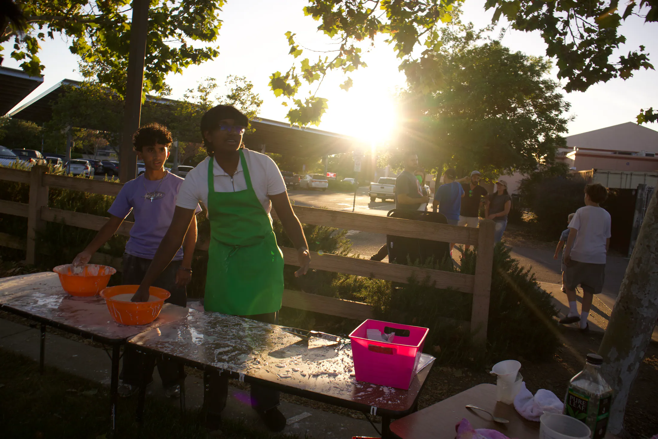 A student volunteer prepares an outdoor activity table in late-afternoon light.