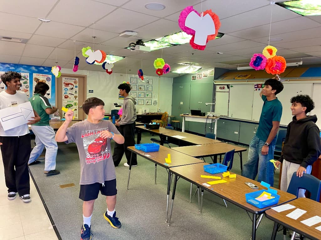 A student tries a hands-on activity while volunteers staff colorful classroom tables at Altamont Creek Open House.